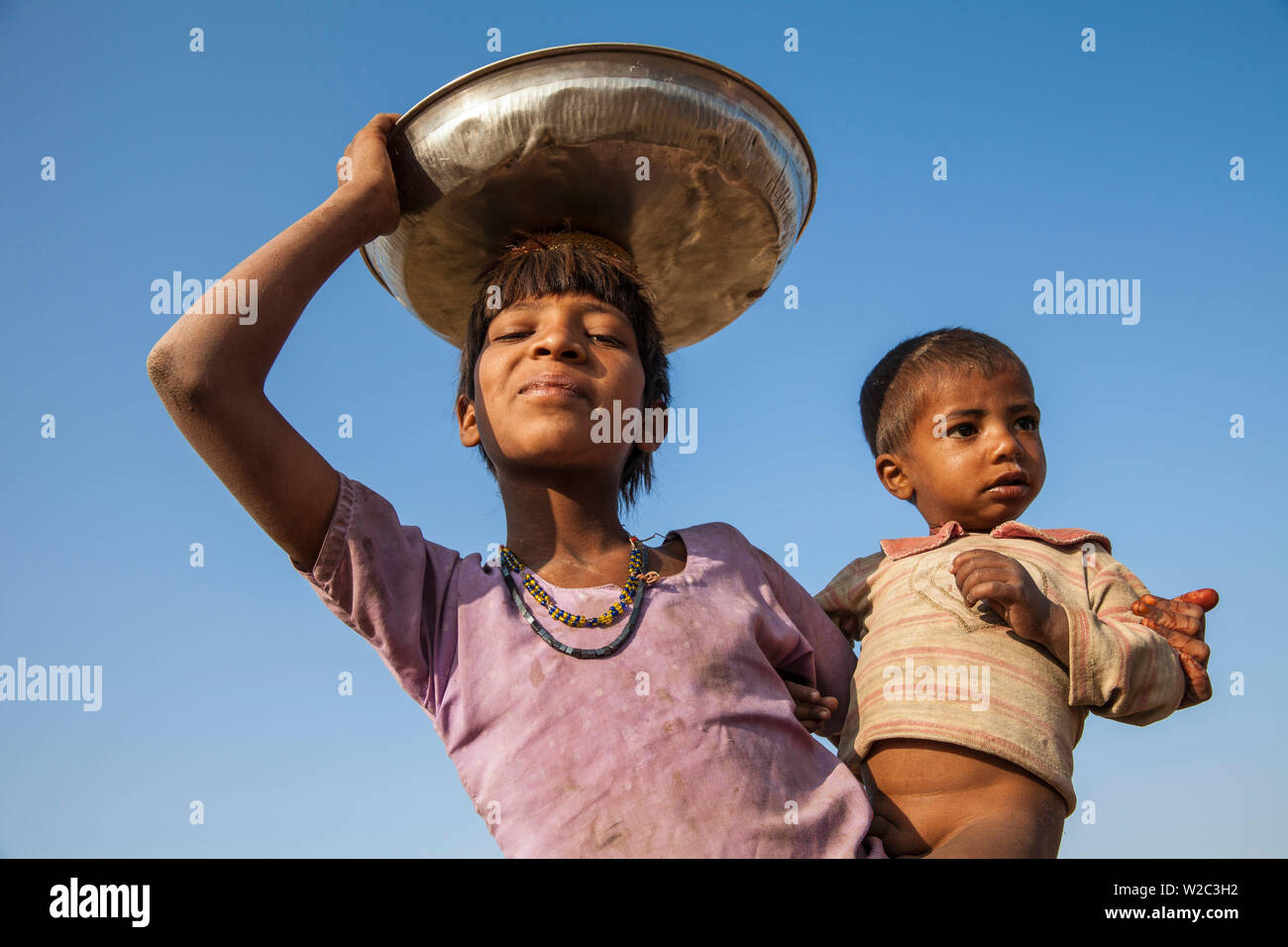L'Inde, Rajasthan, Pushkar, Pushkar Camel Fair, Girl carrying baby chercher de bouse de chameau Banque D'Images