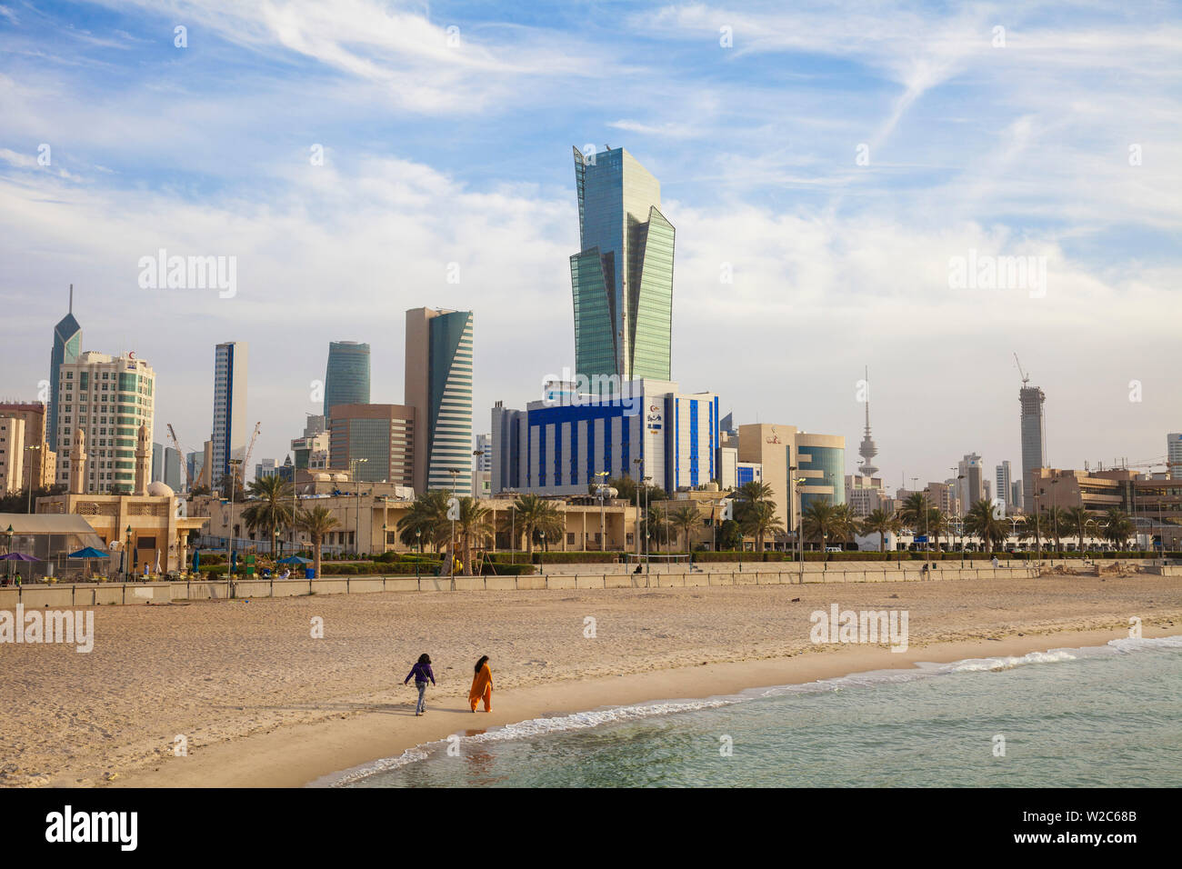 Le Koweït, Koweït City, Sharq, Les Femmes marchant le long d'une plage de la ville sur le golfe Arabique rue avec des bâtiments du centre-ville Banque D'Images