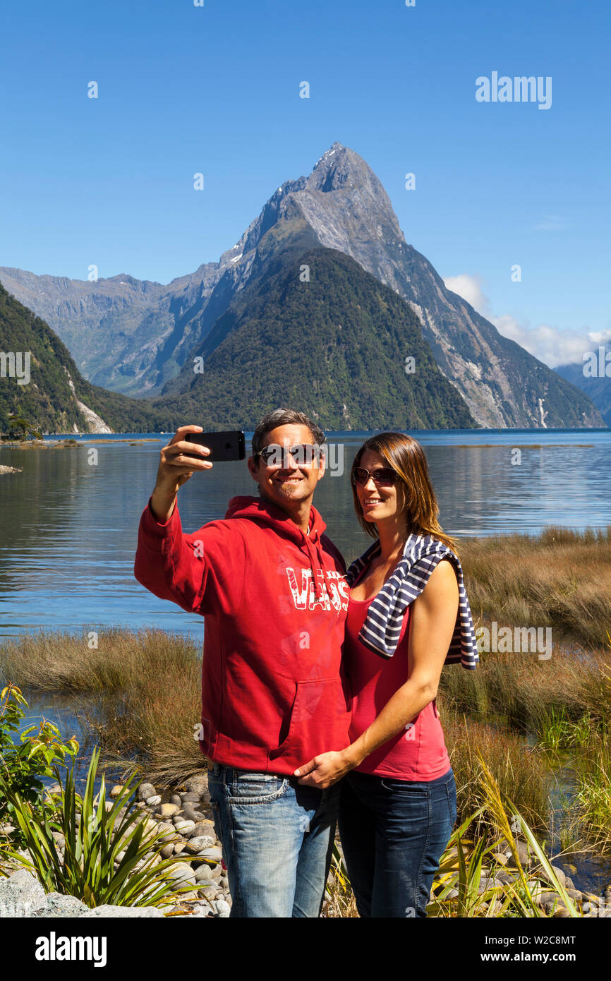 Couple taking self portrait photo, Mitre Peak, Milford Sound, Fiordland National Park, South Island, New Zealand Banque D'Images