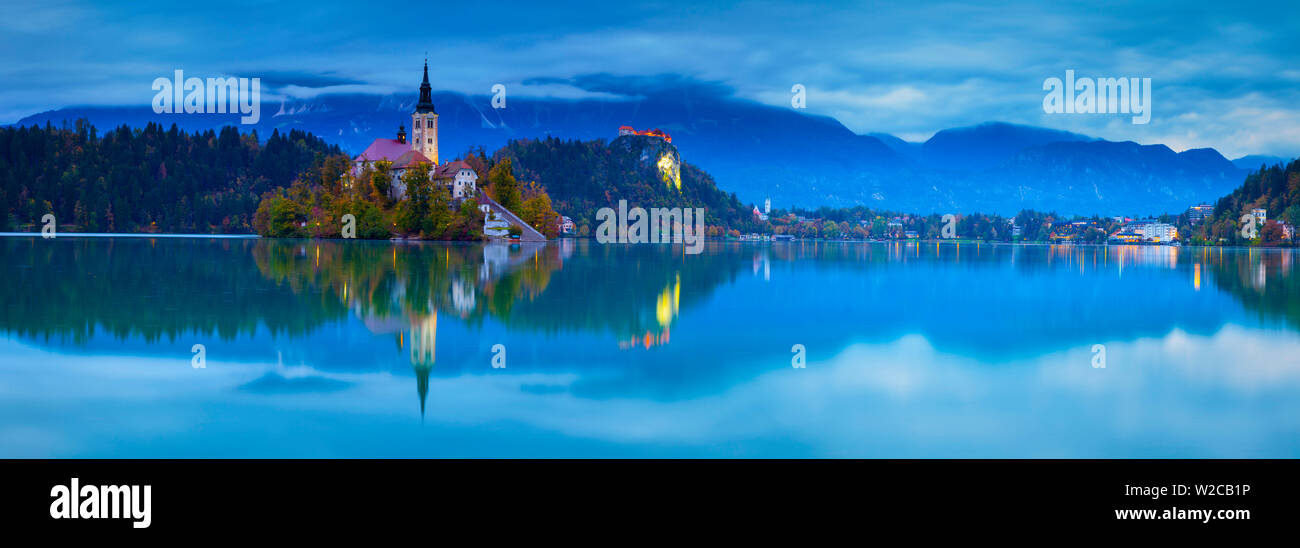L'île de Bled (Blejski Otok) avec l'église de l'Assomption (Cerkev Marijinega vnebovzetja) & Château de Bled allumé à la tombée de la nuit, le lac de Bled, Bled, Haute-Carniole, Alpes Juliennes, en Slovénie Banque D'Images