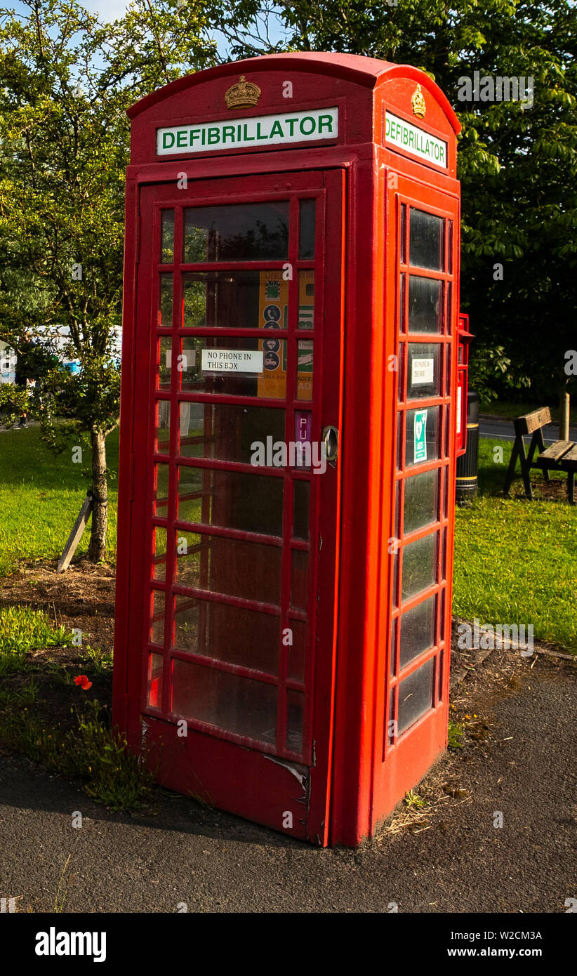 Un ancien téléphone rouge fort qui a été converti en un défibrillateur dans le village de Twemlow Green, Cheshire. Avec le besoin de téléphones publics en baisse, les organismes de bienfaisance de tout le Royaume-Uni ont trouvé une nouvelle utilisation pour le rouge emblématique des cabines téléphoniques en les utilisant comme des foyers pour l'accès du public aux défibrillateurs. Banque D'Images