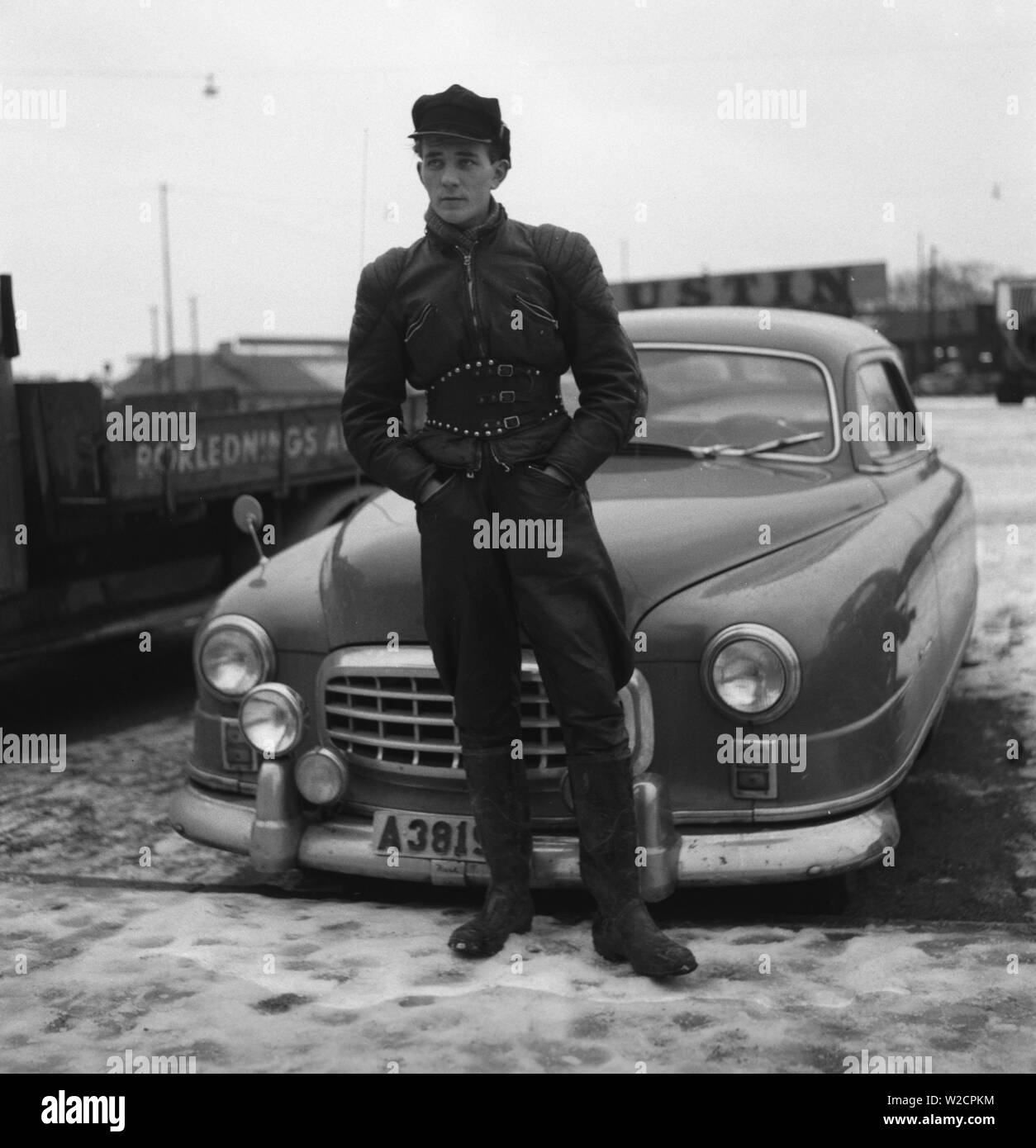 Motocycliste dans les années 1950. Un jeune homme vêtu de la façon typique les motards ont fait dans les années 1950. Tout en cuir. Bottes en cuir, pantalon et veste. A une ceinture et un chapeau typique motocycliste. La Suède Décembre 1954 Banque D'Images