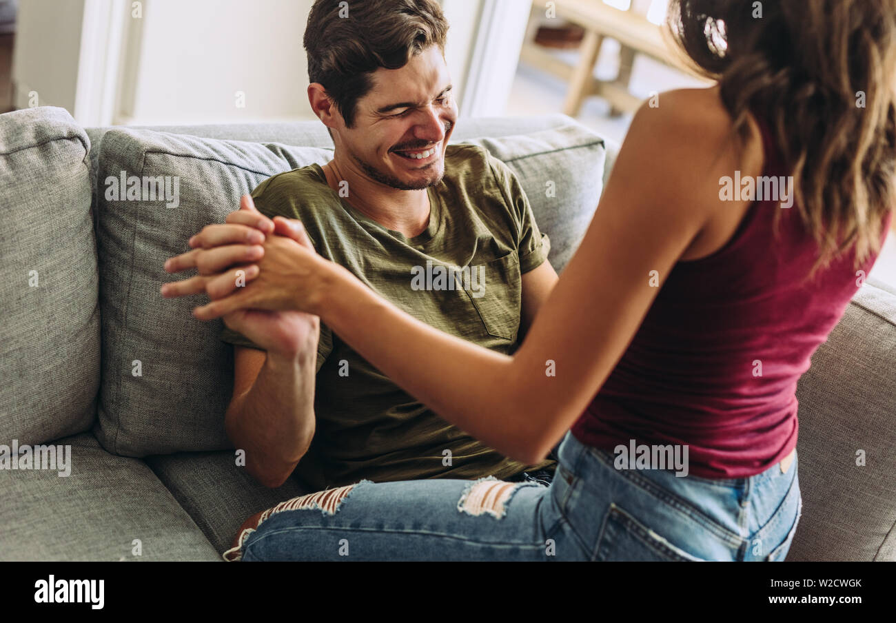 Femme assise sur le haut de son petit ami sur le canapé. Playful Couple avoir un amusement à la maison. Banque D'Images