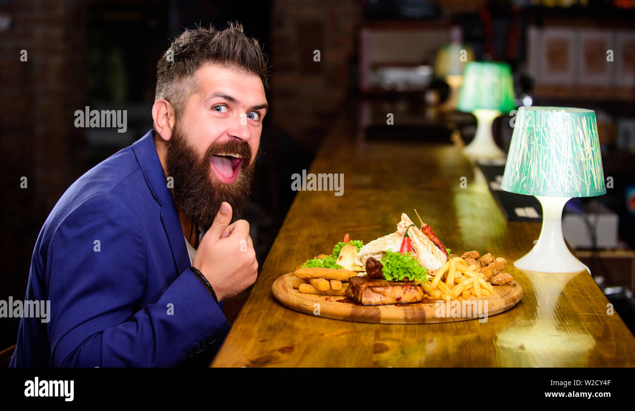 Profitez de repas. Des calories. Vous pourrez vous détendre après une dure journée de travail. Woman costume formel s'asseoir à comptoir bar. L'homme a reçu de pommes de terre frites repas avec viande et poisson, lavash. Il méritent de délicieux repas. Banque D'Images
