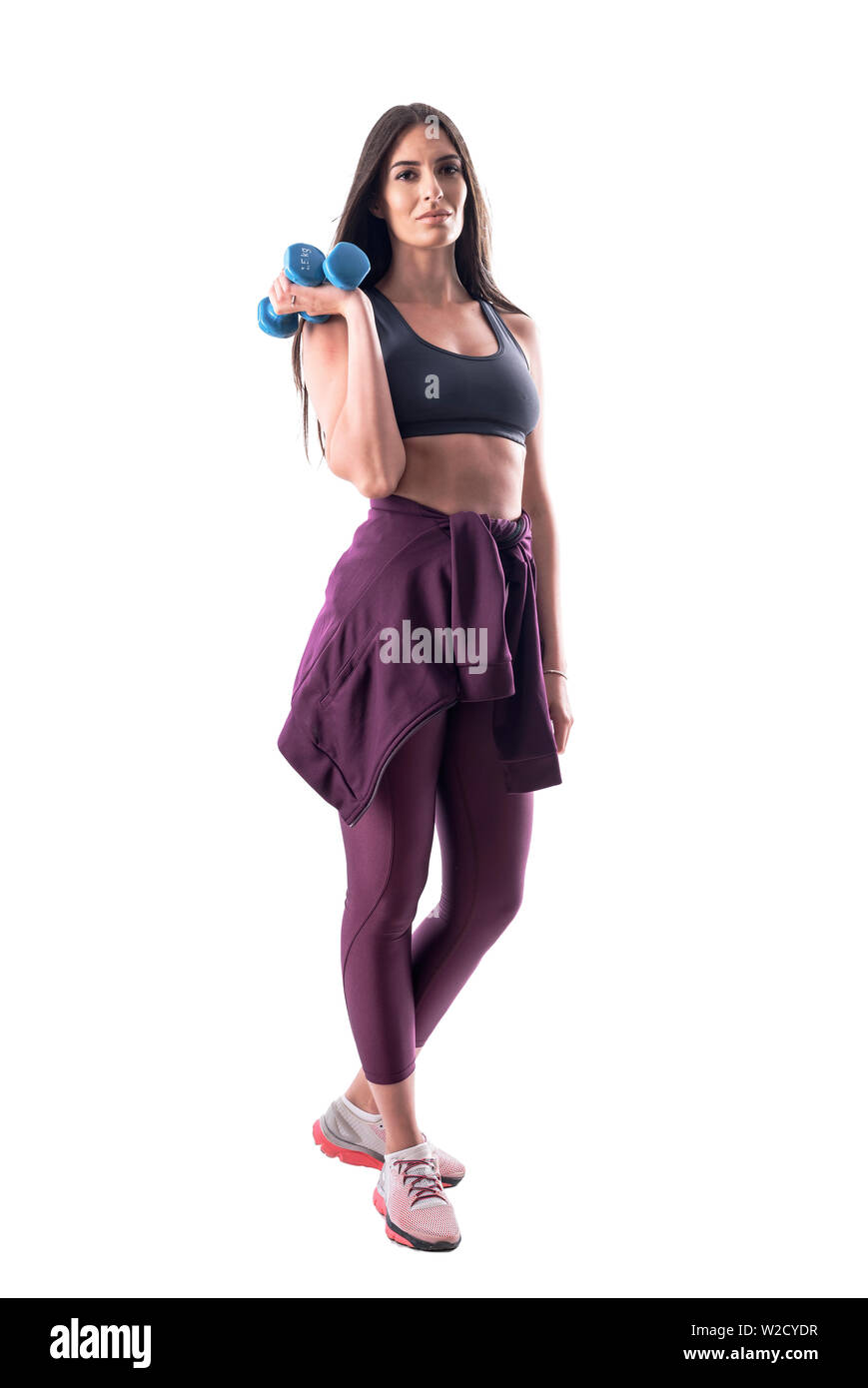 Vue de côté de l'ajustement de la sportive des jeunes actifs dans les vêtements de sport holding dumbbells. Corps plein isolé sur fond blanc. Banque D'Images