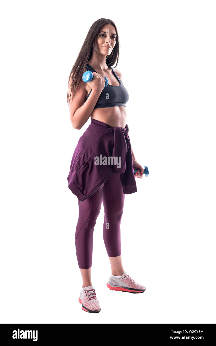L'attractive sporty fit woman doing biceps exercices de bras avec haltère looking at camera. Corps plein isolé sur fond blanc. Banque D'Images