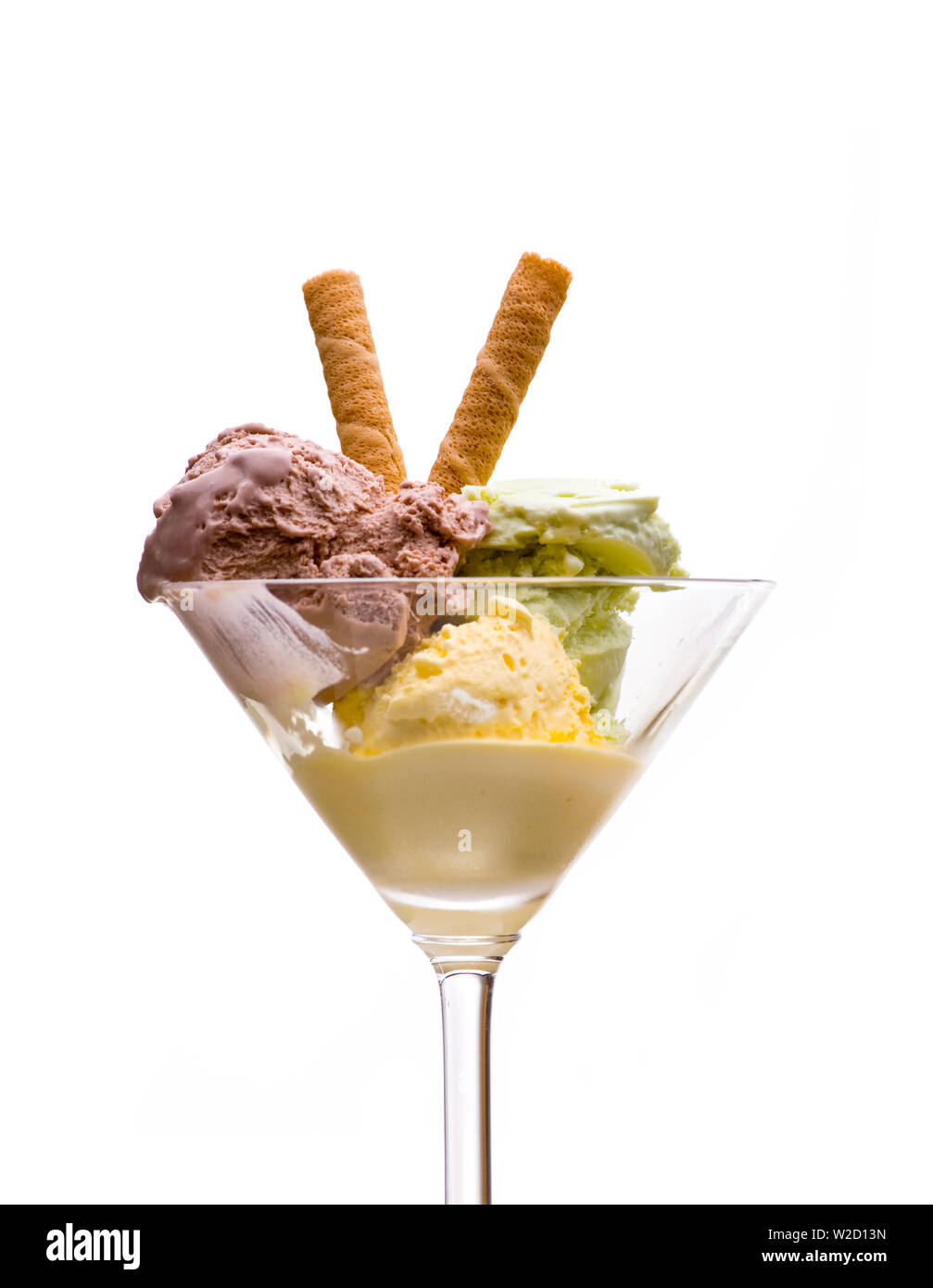 Coupe de glaces : Vue de face de la crème glacée avec du jaune, vert et marron avec de la crème glacée dans un verre à martini sur fond blanc Banque D'Images