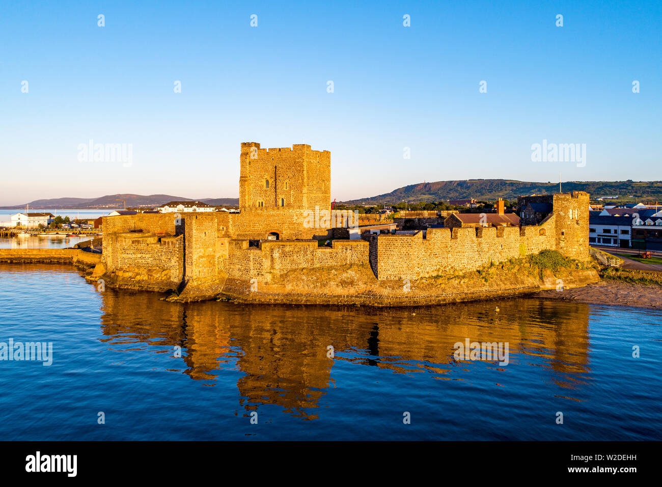 Cité médiévale du château normand à Carrickfergus près de Belfast dans le lever du soleil la lumière. Vue aérienne avec de l'eau reflet Banque D'Images