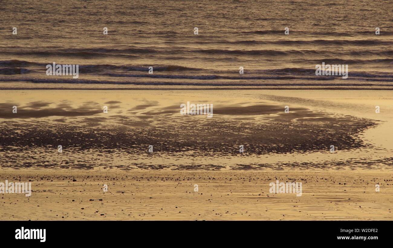 Ruisseau des modèles complexes de sable à marée basse par une mer calme dans la lumière dorée de l'aube, Aberdeen, Écosse, Royaume-Uni. Banque D'Images