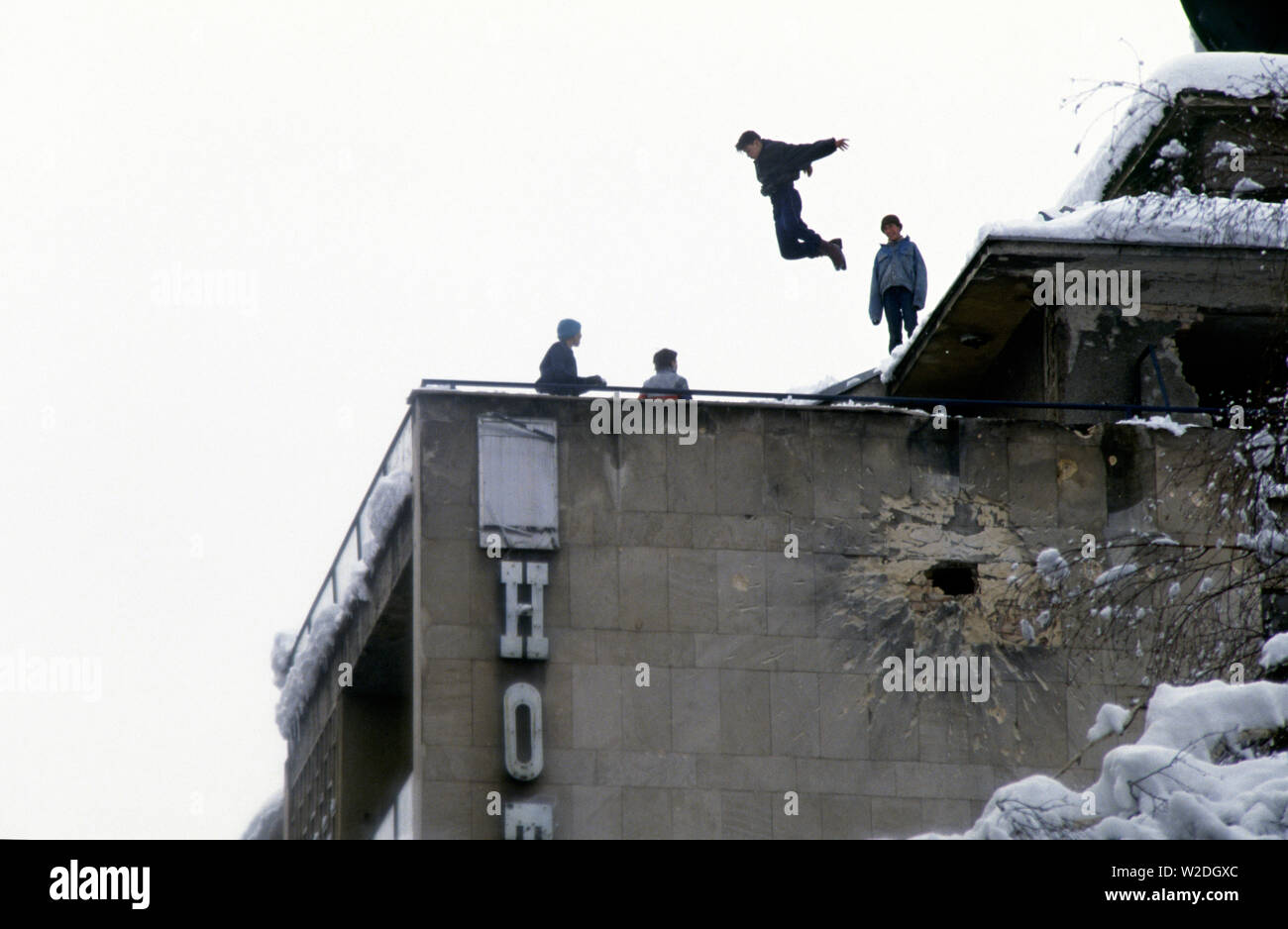 28 mars 1993 pendant le siège de Sarajevo : les jeunes garçons jouent sur le toit de l'Hôtel Europa, haut au-dessus de Jugoslovenske Narodne Armije Zelenih beretki (rebaptisée rue après la guerre). Au-dessous d'eux est un grand trou dans le mur, causée par un obus de mortier ou d'artillerie. Banque D'Images