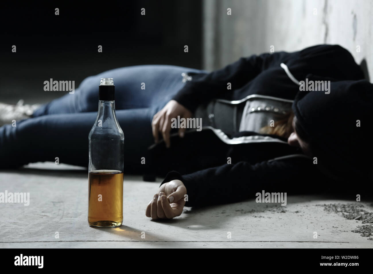 Drunk girl dormir sur le plancher dans un garage avec une bouteille  d'alcool boire en premier plan Photo Stock - Alamy