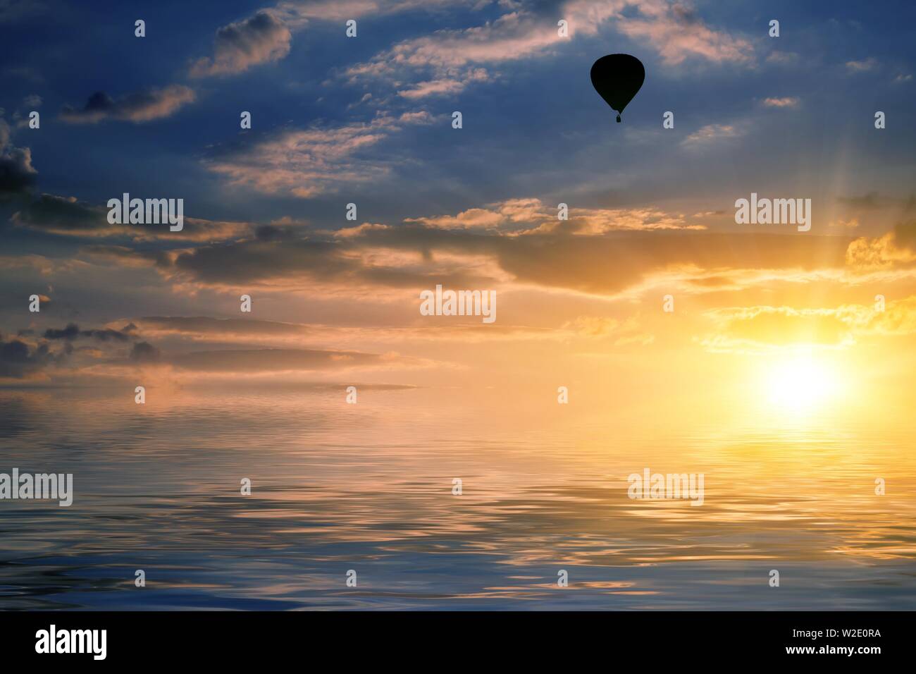 Paysage naturel avec ciel nuageux au coucher du soleil et l'air balloon reflète dans l'eau Banque D'Images