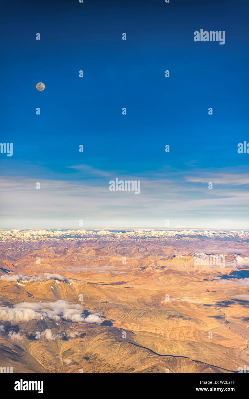 Pleine lune sur les montagnes arides de l'intérieur de la gamme du Zanskar Himalaya, l'Inde. Prises d'un avion sur un début de juillet matin. Orientation Portrait. Banque D'Images