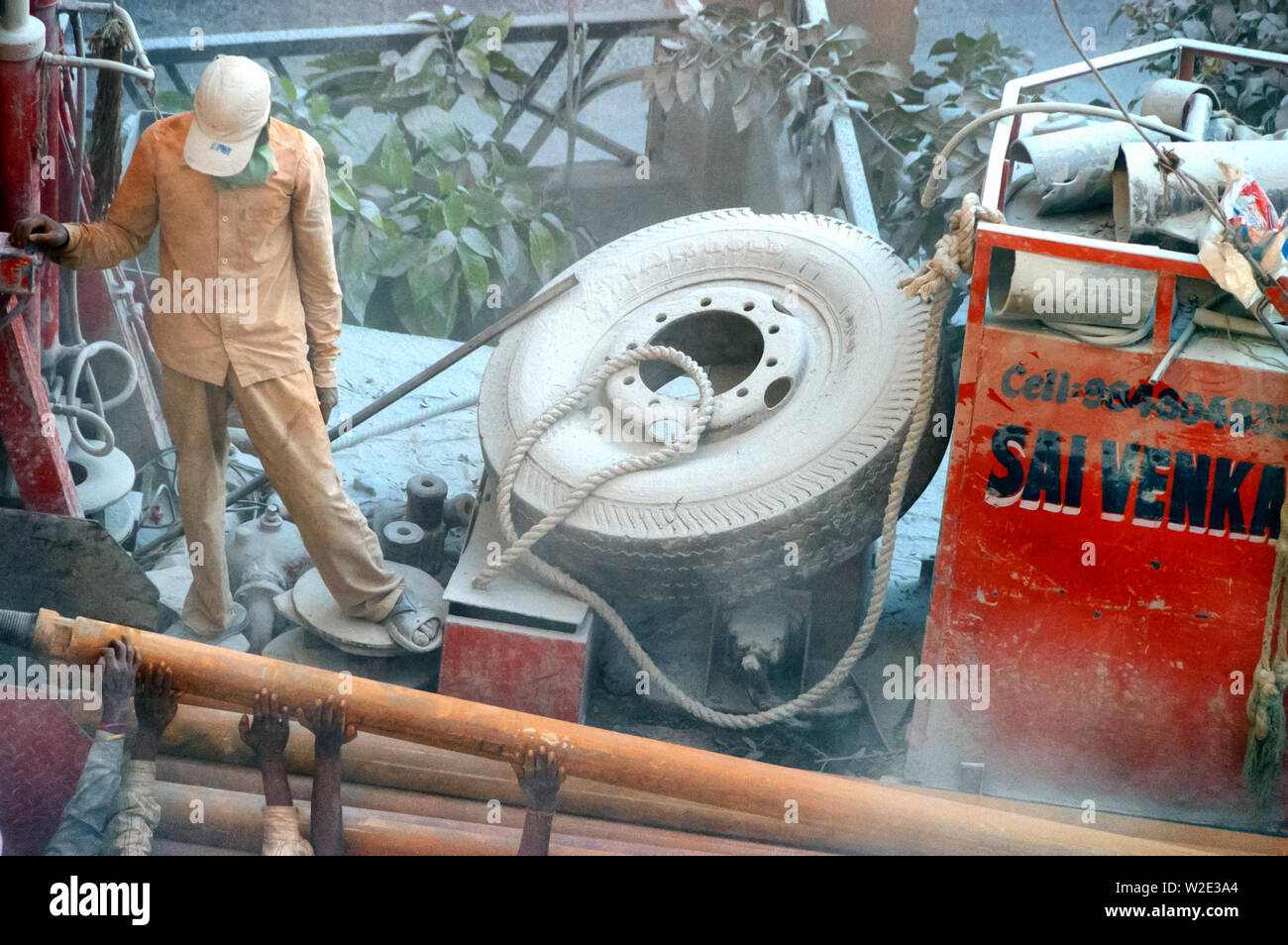 Close up des mains des travailleurs le chargement/déchargement des tuyaux métalliques de/à partir d'un mobile de forage, le forage pour trouver de l'eau au sol à Hyderabad, Inde. Banque D'Images