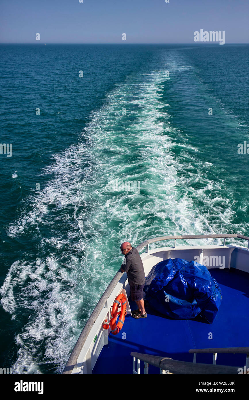 Un passager surplombant la mer depuis l'arrière d'un chenal traversier à partir de la Bretagne, France Banque D'Images
