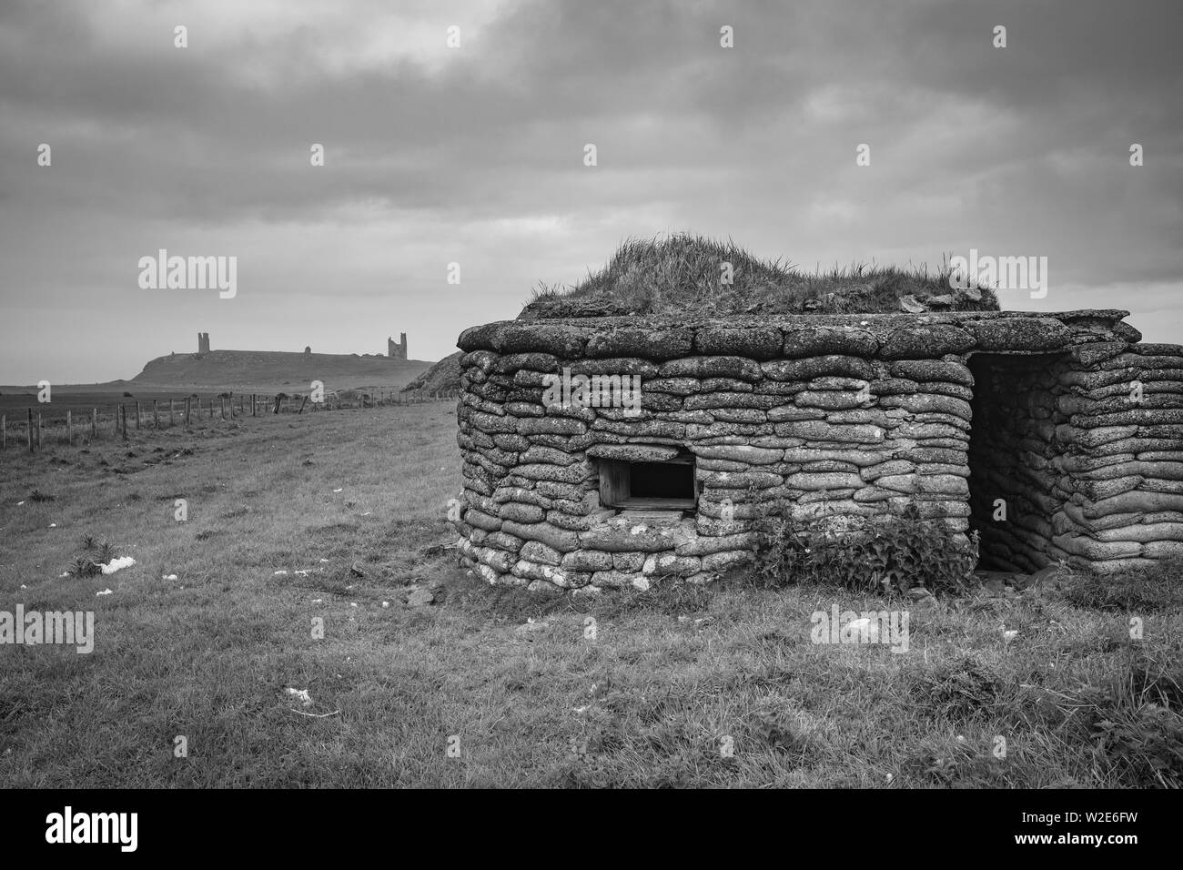 Guerre Mondiale deux Pilllbox avec Château de Dunstanburgh dans la distance, Northumberland, Angleterre Banque D'Images