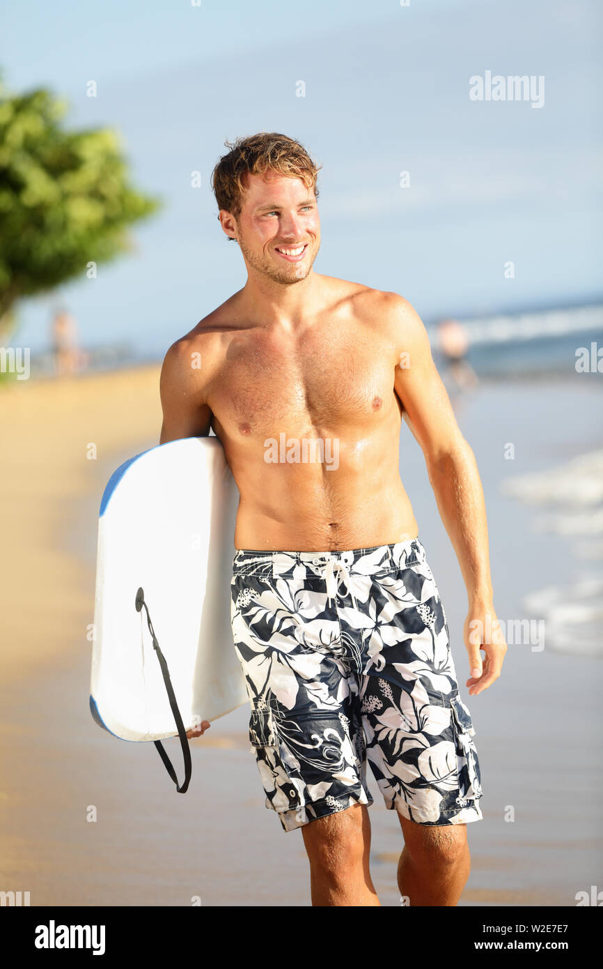 Man on beach holding body surf bodyboard faisant sports d'eau. Activités de plein air voyages vacances d'été libre de droit avec beau modèle sport fitness mâle smiling happy on tropical beach. Banque D'Images