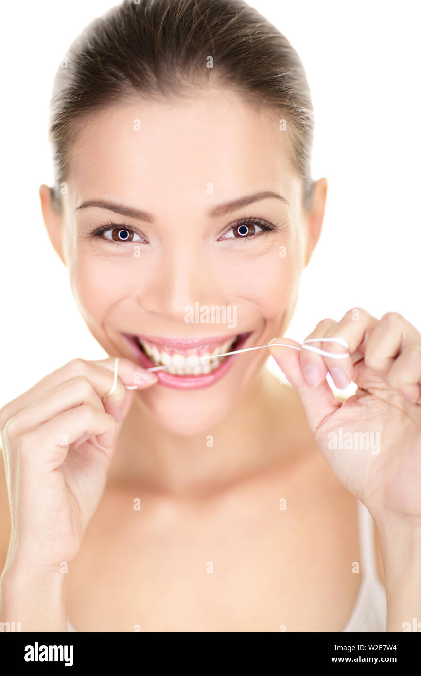 Woman flossing teeth smiling en utilisant la soie dentaire. Happy girl avec dents parfaite et sourire à pleines dents. Portrait de soins dentaires de la belle asiatique multiraciale Caucasian female isolé sur fond blanc 20s. Banque D'Images