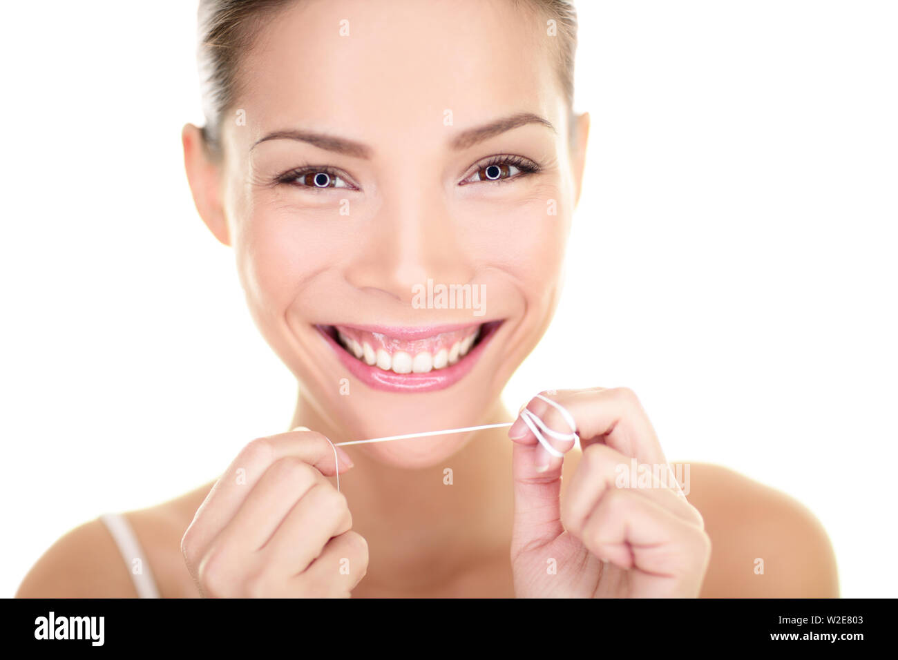 Fil dentaire - femme flossing teeth smiling happy avec dents parfaite et sourire à pleines dents. Concept de soins dentaires avec de belles asiatiques multiraciale Caucasian female model isolé sur fond blanc. Banque D'Images