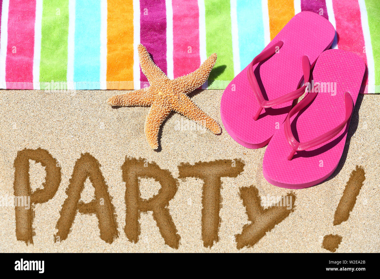 Beach Party concept amusant voyage. Partie écrit dans le sable avec de l'eau à côté de serviette de plage, sandales d'été et d'étoiles. Locations de vacances d'été et le soleil fond. Banque D'Images