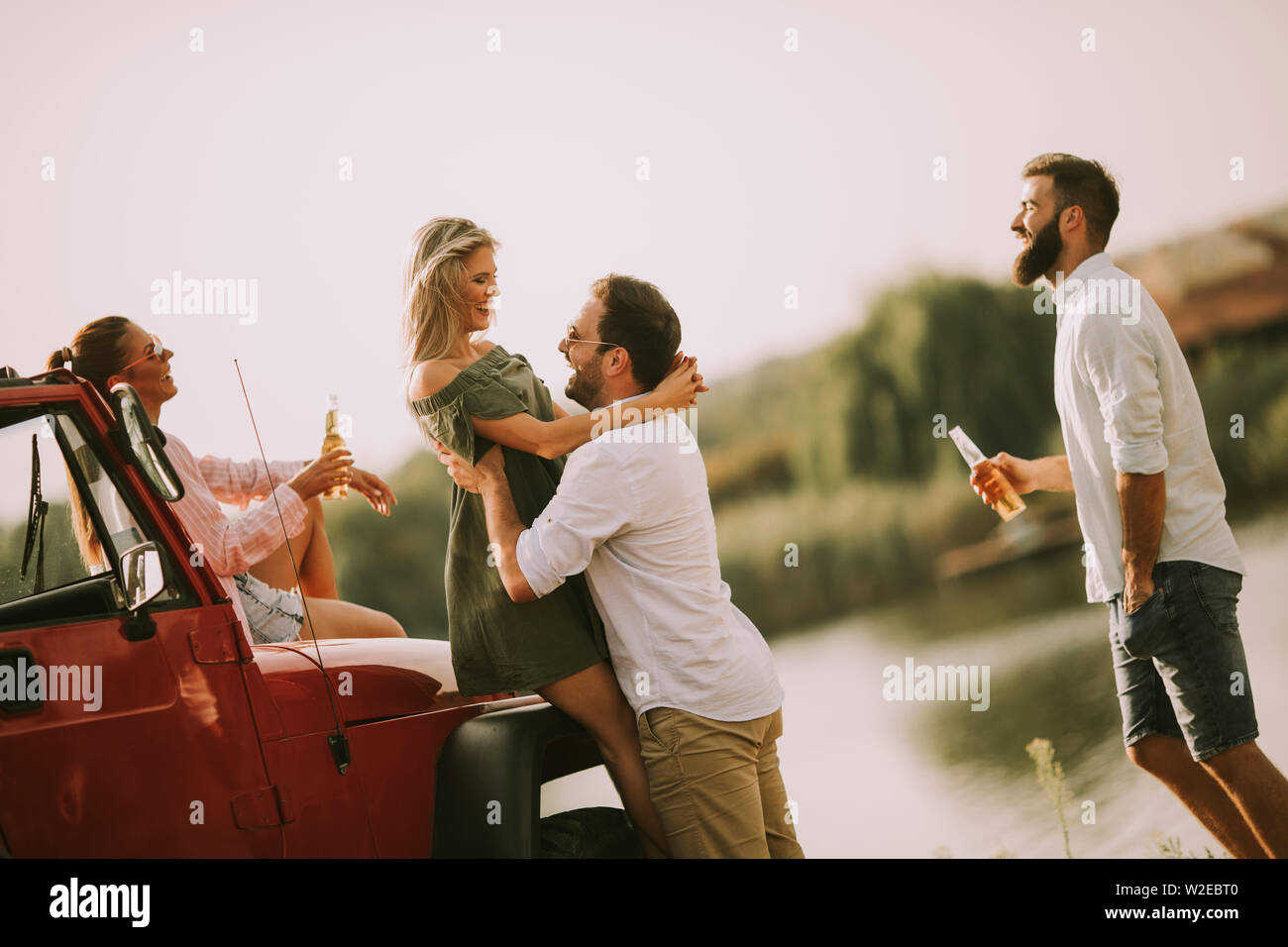 Quatre jeunes gens s'amuser en voiture décapotable par river Banque D'Images