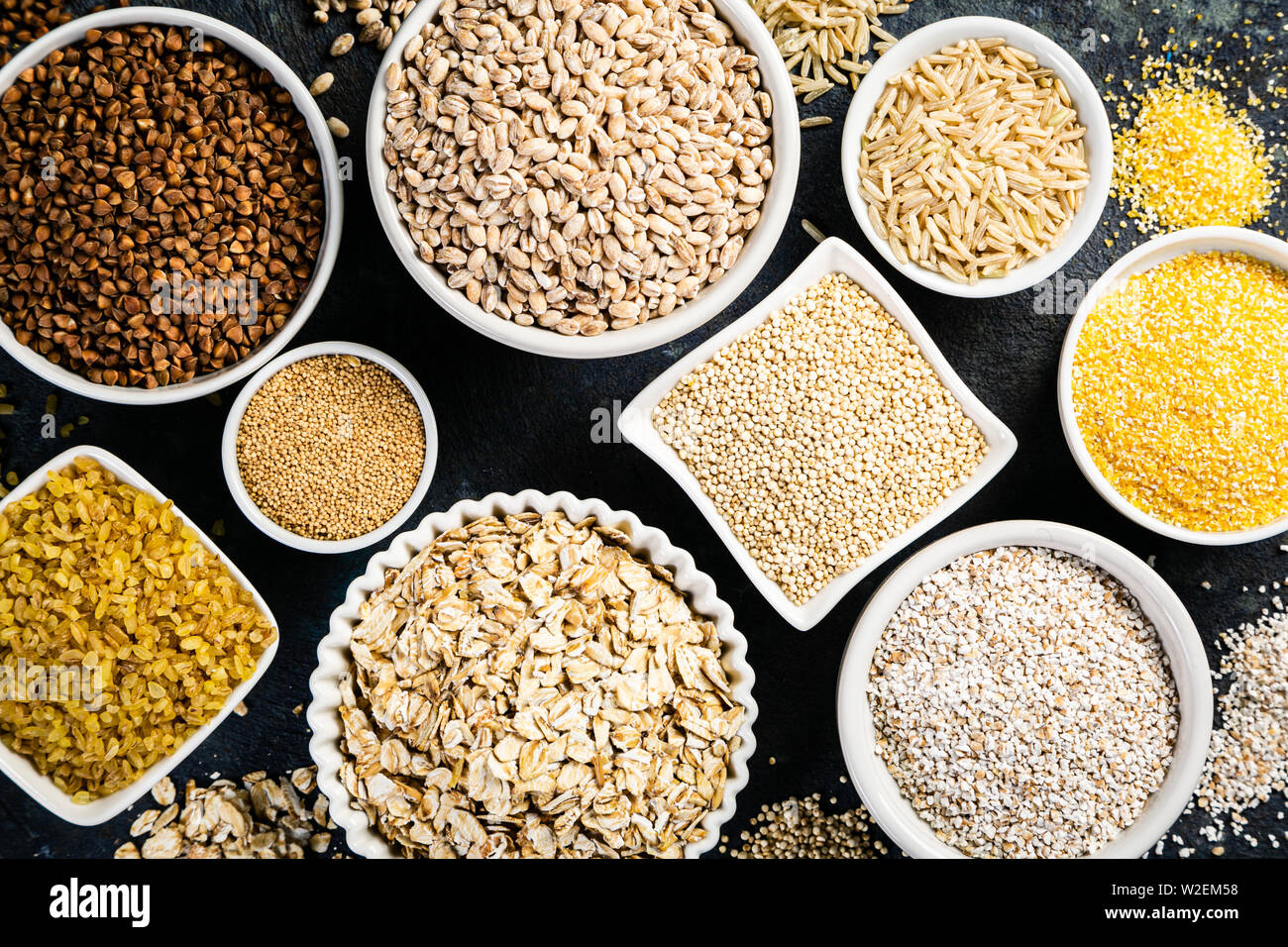 Sélection de grains entiers dans des bols blancs : riz, avoine, sarrasin, boulgur, porridge, orge, quinoa, amarante Banque D'Images
