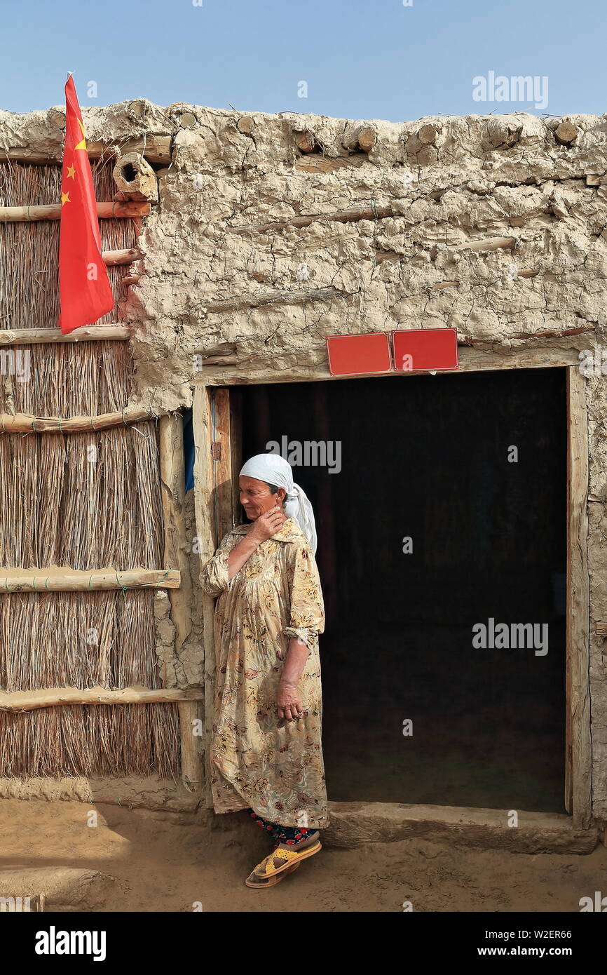 Uyghur femme à ses roseaux et de la porte de la hutte de boue-Comté de Keriya-Xinjiang-Chine-0294 Banque D'Images