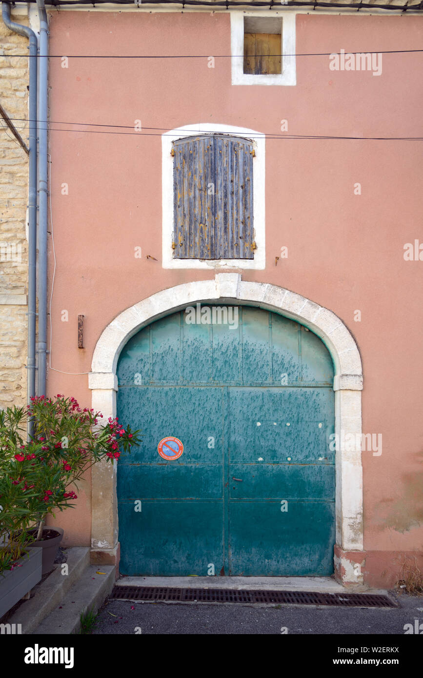 Ancienne porte de garage turquoise et orange en façade de l'ancienne maison de village de charme Goult Luberon Provence France Banque D'Images