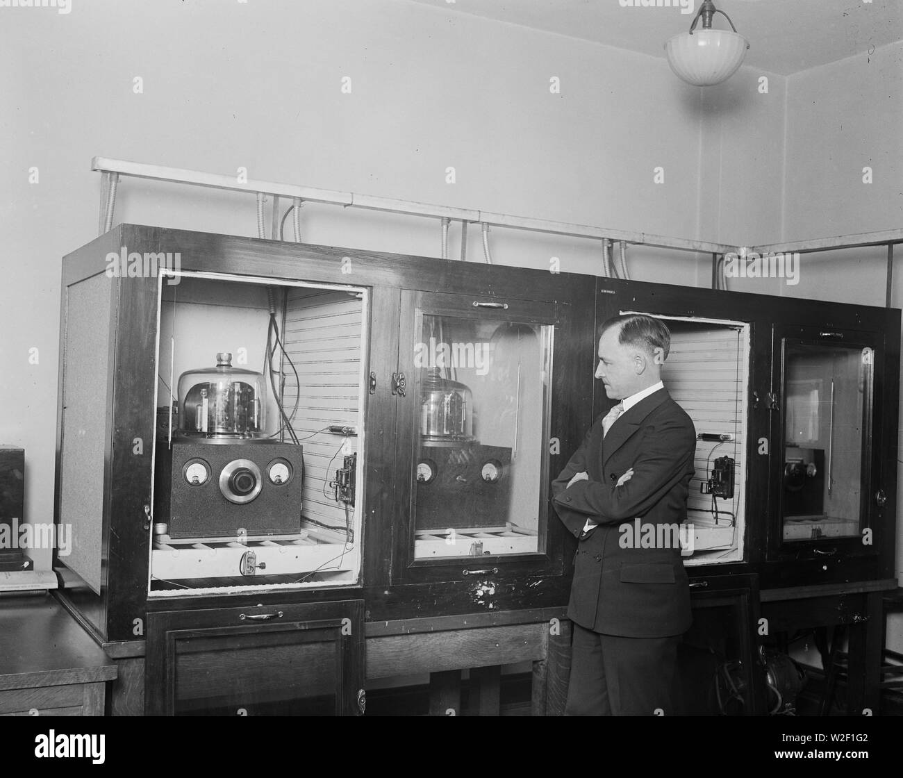 Homme avec un groupe de 100 kHz oscillateurs à cristal de quartz qui a servi comme le U.S. National fréquence primaire standard en 1929 ca. 1930 Banque D'Images