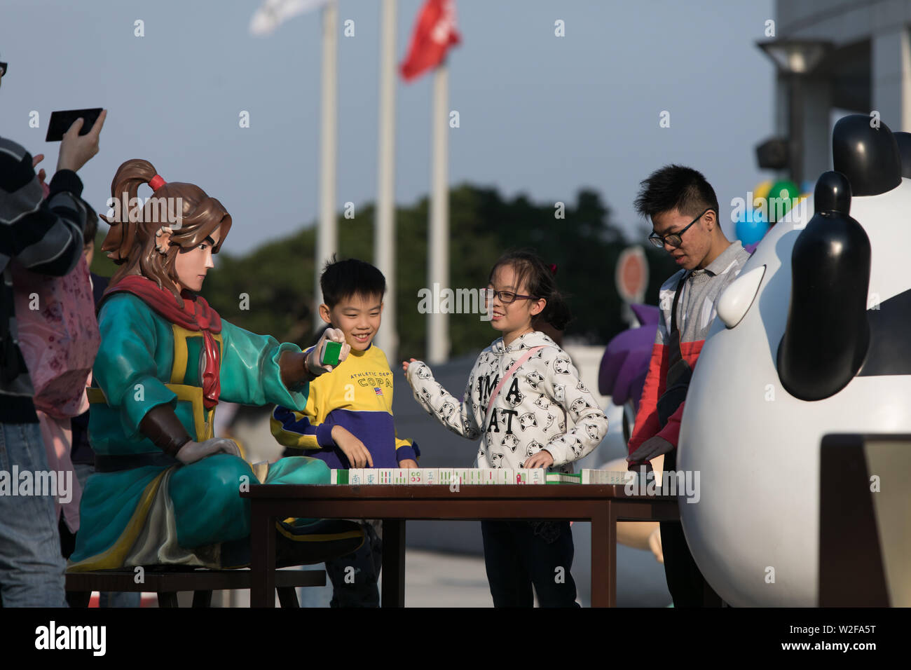 Les enfants posant pour une photo à côté de personnages de dessins animés et un jeu de Mahjong Banque D'Images