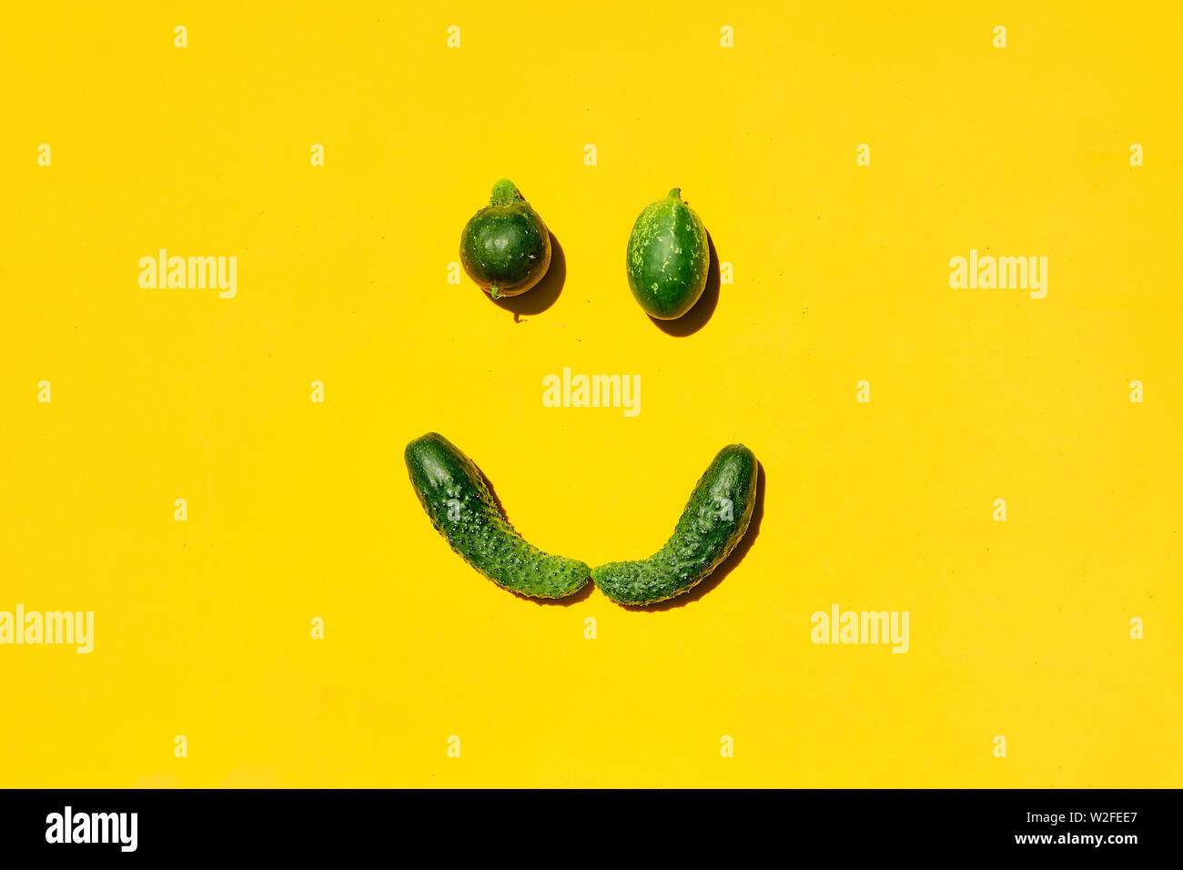 Différentes tailles et formes des concombres sur un fond jaune forme un visage souriant. Sourire, le visage, le paris, Smiley, émoticone joyeux, heureux, souriant emoji icônes emoji. Banque D'Images