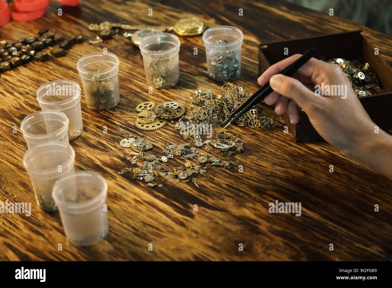 Girl sortes de rapports. L'artisan crée des bijoux. Fabriqué à la main avec des pincettes et roues dentées. Travailler avec des pinces sur le lieu de travail. Les mains sur la table en bois Banque D'Images