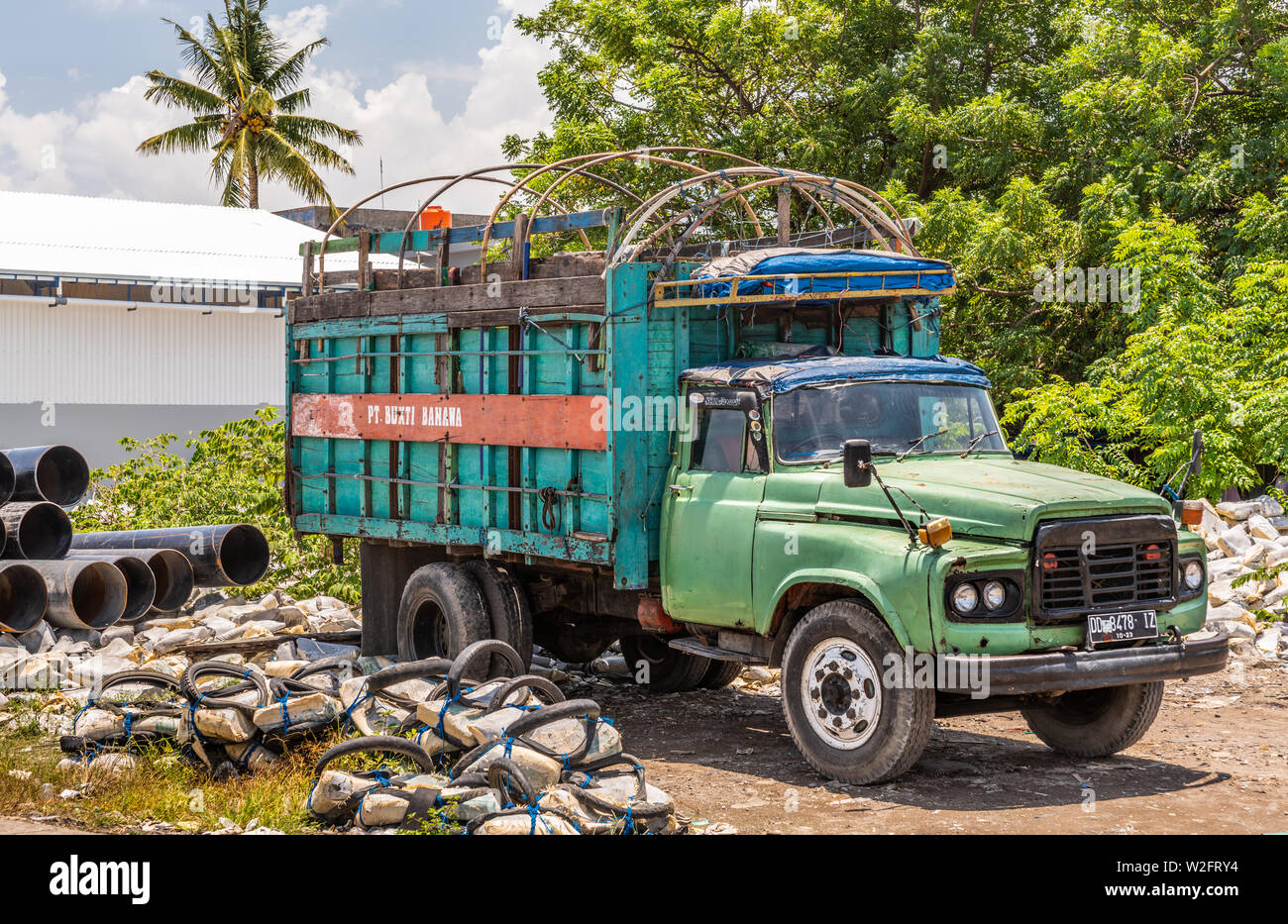 Makassar, Sulawesi, Indonésie - 28 Février 2019 : Paotere Vieux Port. Closeup of old green truck garé en face de la corbeille parmi le feuillage vert. Banque D'Images