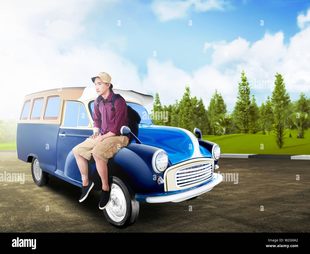 Asian man in hat avec sac à dos, assis sur le capot de la voiture de route avec des arbres verts et fond de ciel bleu. Concept de voyage Banque D'Images