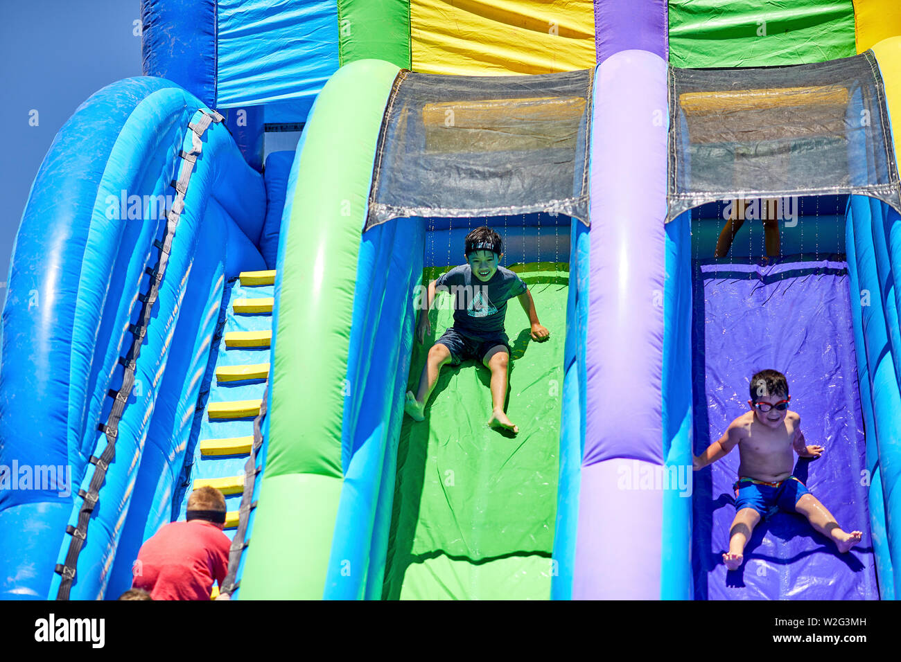 Prescott, Arizona, USA-Juillet 6, 2019 : jeune garçon en glissant sur un toboggan gonflable à la guerre de l'eau, sur le Mile High Middle School en champ downto Banque D'Images