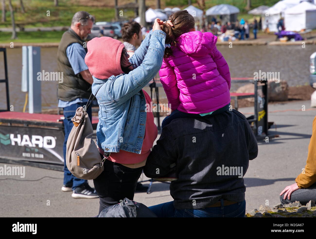 Meriden, CT USA. Apr 2019. Fête des Jonquilles. Maman les cheveux de fille de fixation sur un endroit frais breezy day. Banque D'Images