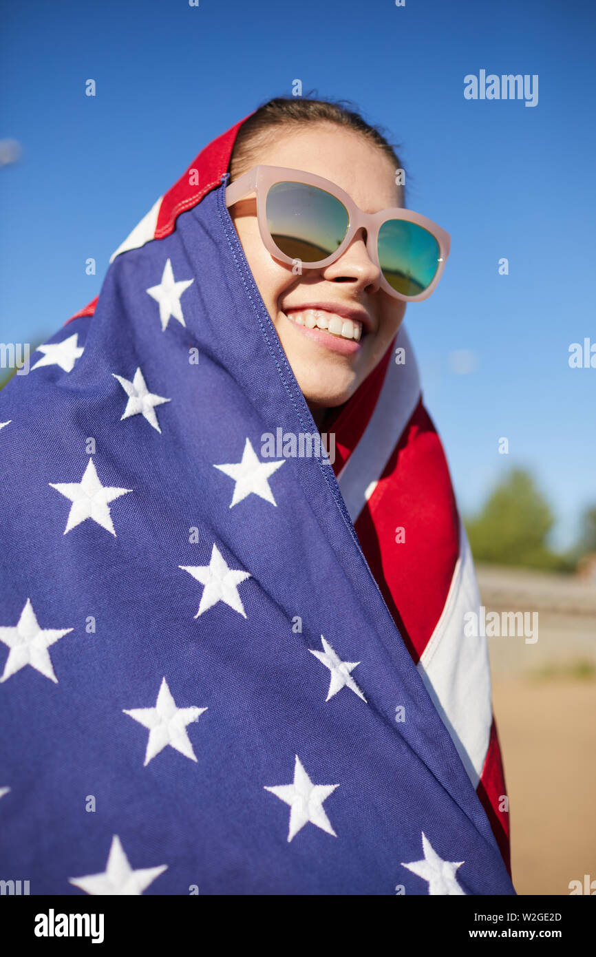 Heureux heureux American girl in sunglasses blottis en regardant le drapeau américain consacré à la parade date de l'indépendance Banque D'Images