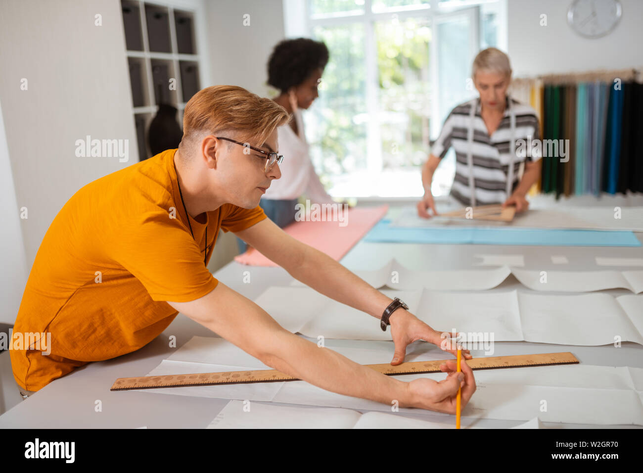 Créateur de mode concentré. Vue latérale du portrait d'une jeune Fashion designer, concentré dans un atelier de fabrication d'un modèle papier Banque D'Images