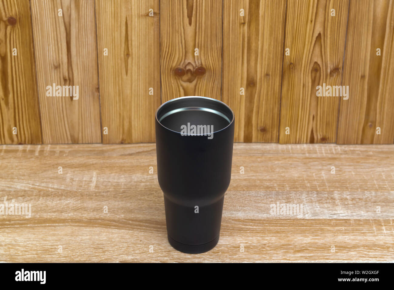 Couleur Noir acier inoxydable gobelet ou tasse de stockage à froid et à chaud sur fond de bois. Banque D'Images