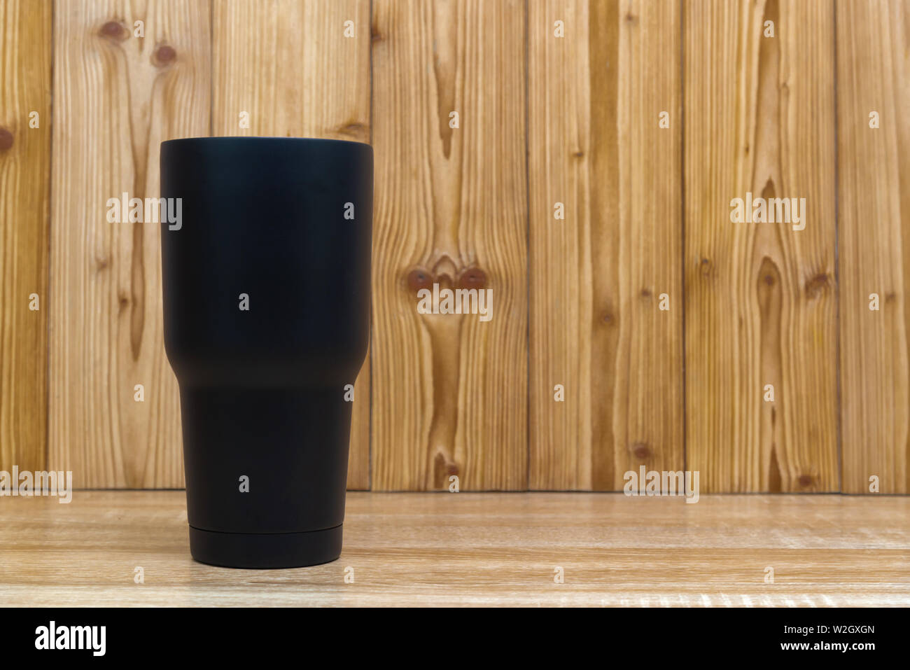 Couleur Noir acier inoxydable gobelet ou tasse de stockage à froid et à chaud sur fond de bois. Banque D'Images