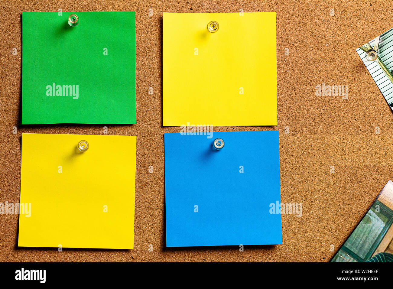 Tableau de Liège/Bulletin Board et des notes autocollantes vierges en jaune, vert et bleu, disposées de façon très ordonnée. Super pour la rédaction. Banque D'Images