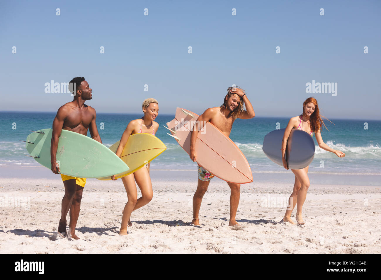 Groupe d'amis à marcher avec une planche de surf sur la plage Banque D'Images