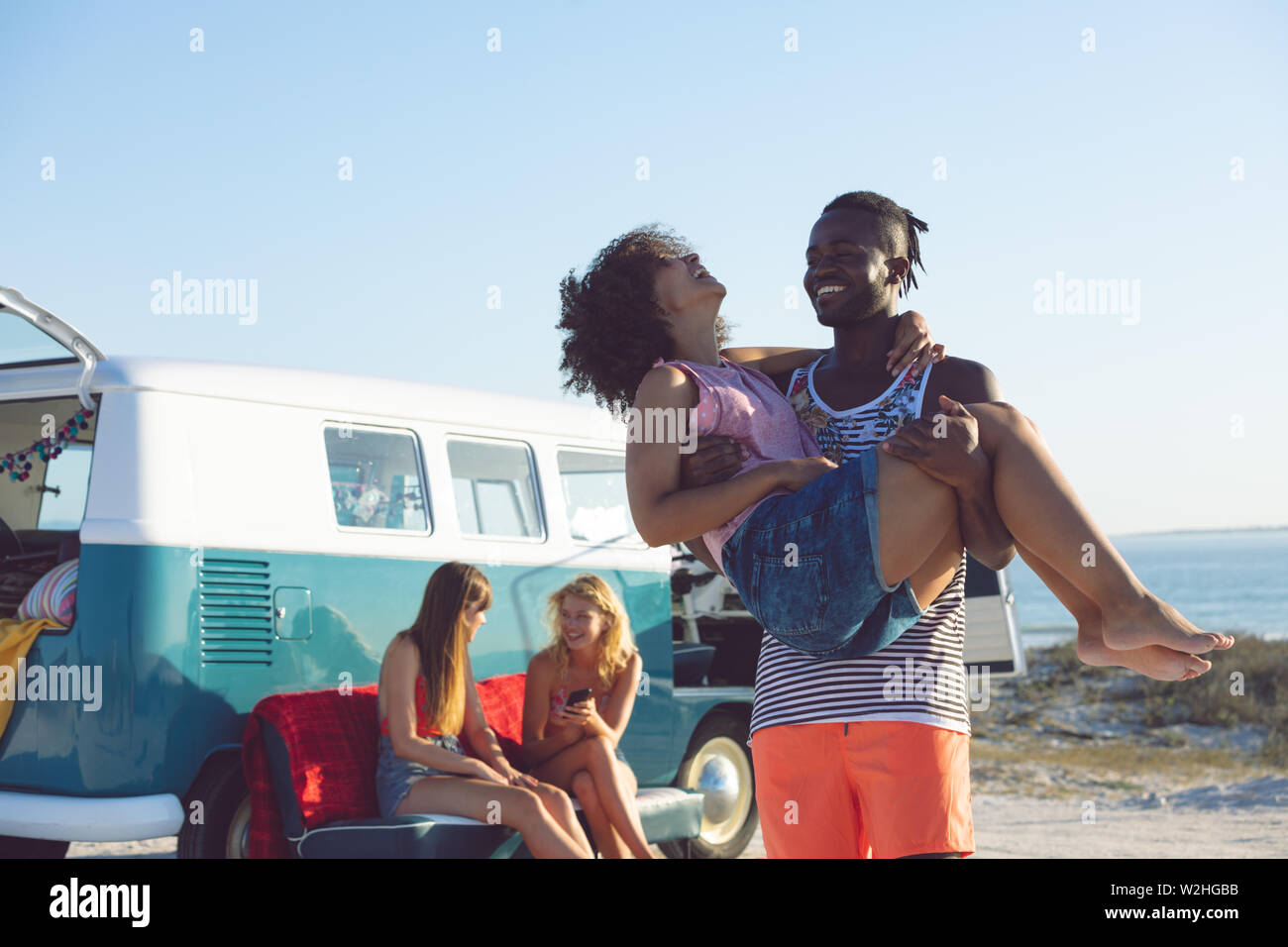 Femme Homme tenant dans ses bras près de camping-van at beach Banque D'Images