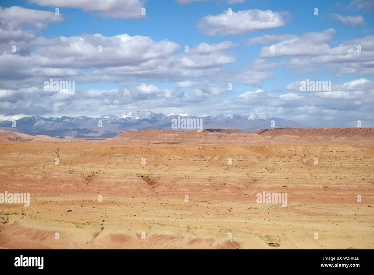 Climat aride dans paysage de désert contre ciel nuageux ciel bleu et enneigés des montagnes du haut atlas. Ouarzazate, Maroc. Banque D'Images