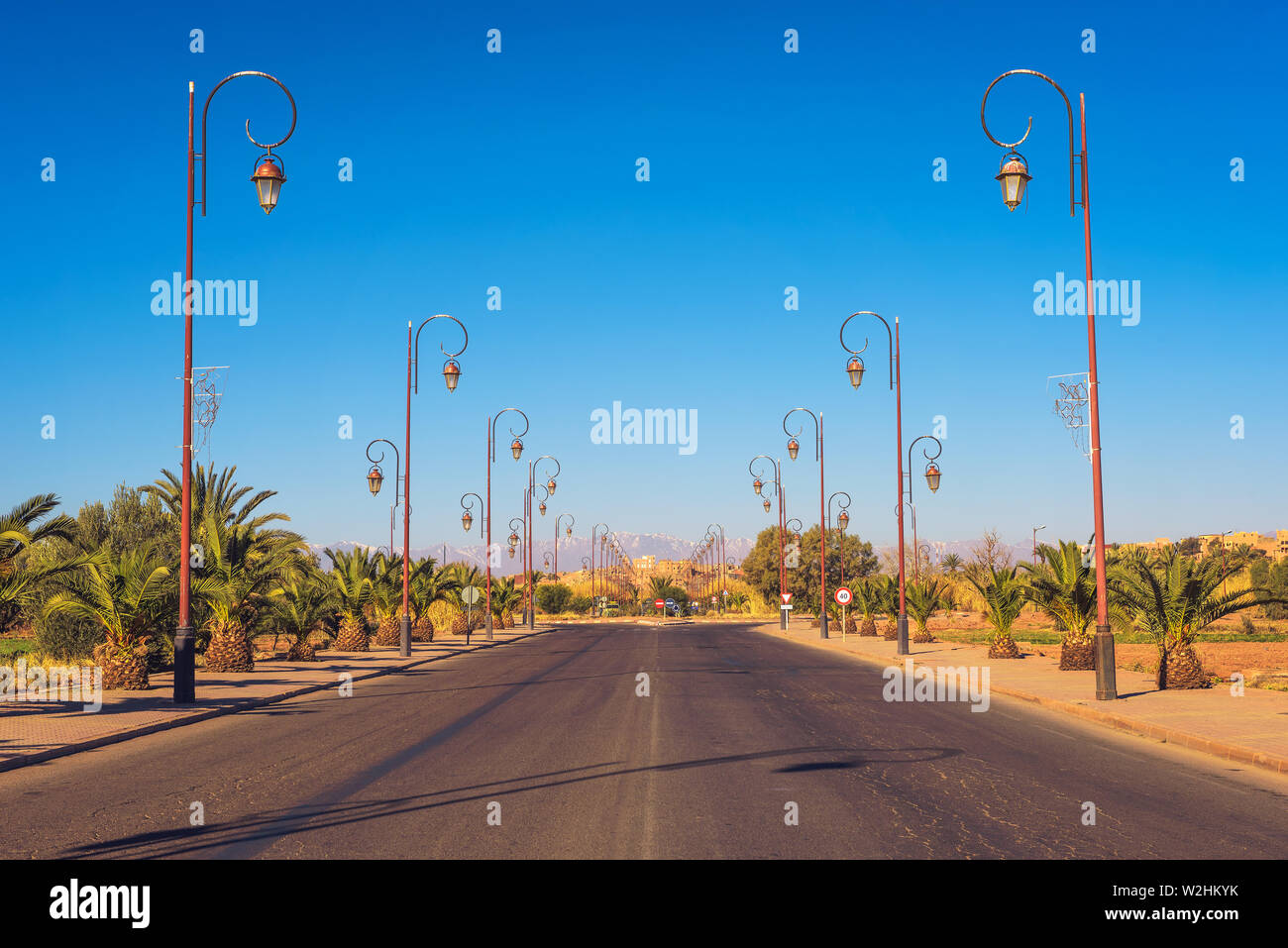 Route avec rangée de lampadaires de style dans le centre de Ouarzazate, Maroc Banque D'Images