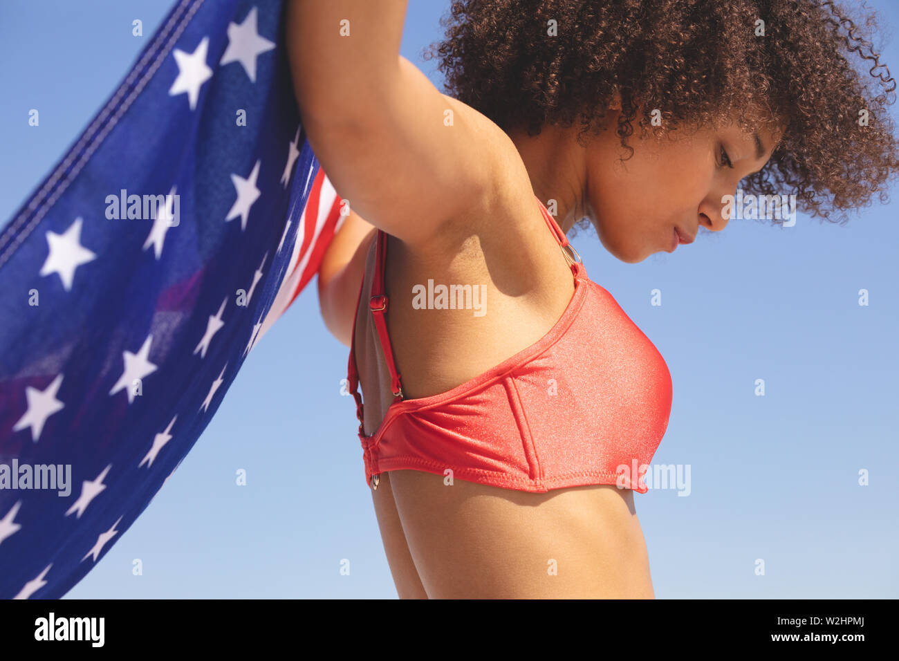 Woman in bikini holding drapeau américain sur la plage Banque D'Images