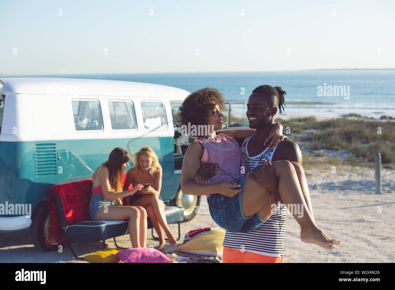 Femme Homme tenant dans ses bras près de camping-van at beach Banque D'Images