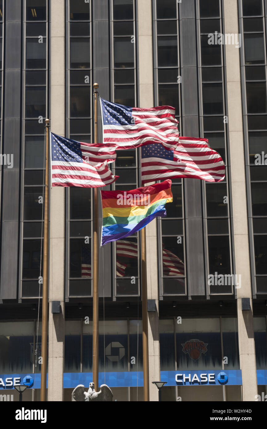 Drapeau arc-en-ciel (LGBTQ) voler avec des drapeaux américains en face d'un immeuble de bureaux en l'honneur de la World Pride mois marquant le 50e anniversaire de la Révolte de Stonewall qui marque le début du mouvement des droits des homosexuels à New York City. Banque D'Images