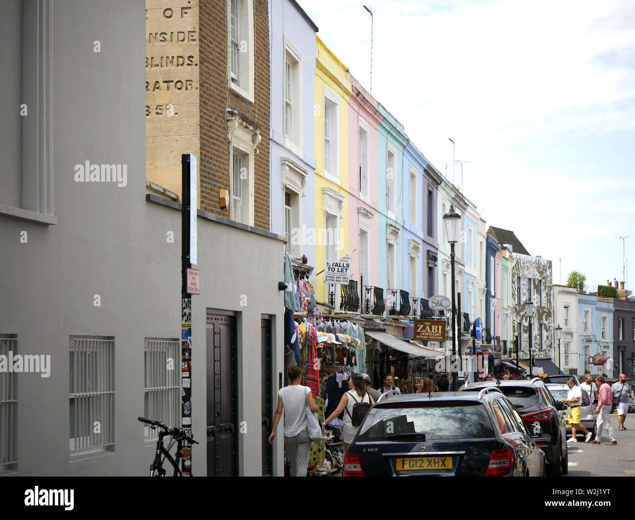 Maisons pastel, des voitures en stationnement et des personnes dans Portobello Road, Londres, Royaume-Uni. Banque D'Images