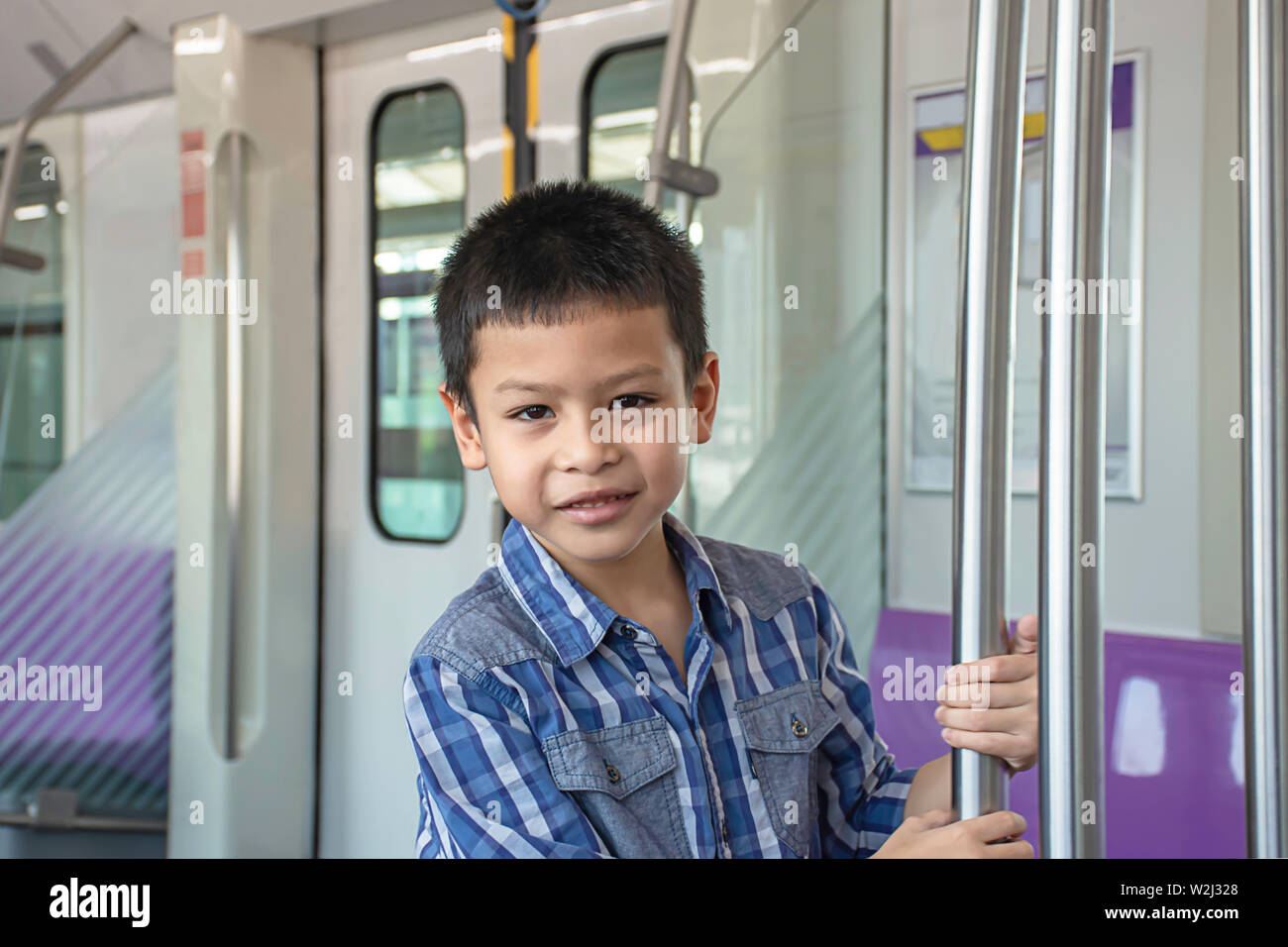 Asian boy holding poteaux en acier inoxydable dans le train. Banque D'Images